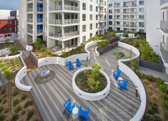 Apartments in Woodland Hills, CA - The Q Variel - Outdoor Courtyard with Chairs, Tables, Beautiful Landscaping, and Views of Patios/Balconies