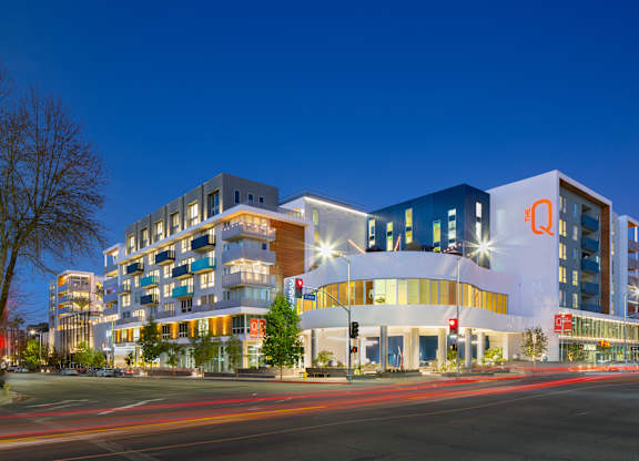 A modern building with a large white circular entrance is illuminated at night.