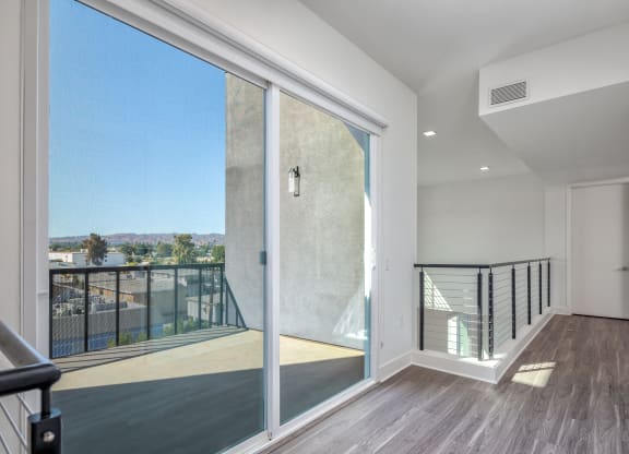 a large glass door opens to a balcony with a view of the city