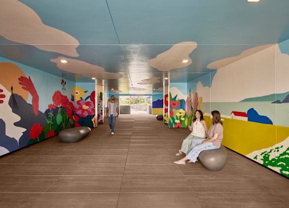 Two women sitting on exercise balls in a room with colorful murals.