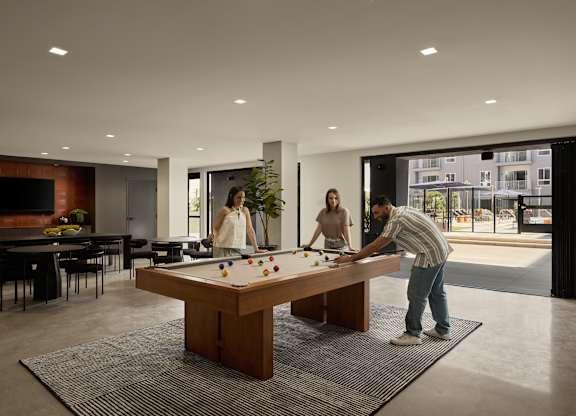 A man is playing pool with two women in a modern room.