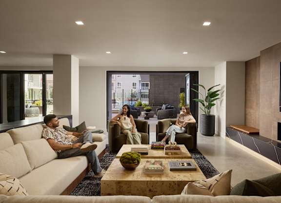 Three people are sitting on a couch in a modern living room.