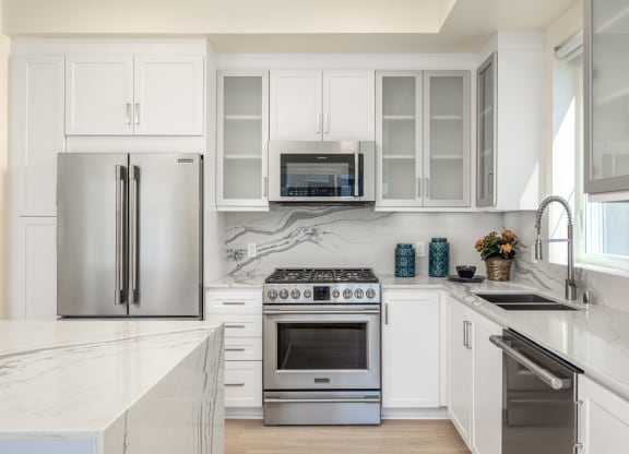 a white kitchen with stainless steel appliances and white cabinets