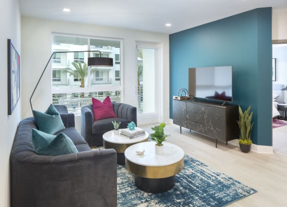 Pet-Friendly Apartments in Woodland Hills, CA - The Q Variel - Living Room with Luxury Vinyl Plank Flooring, a Large Window, and Access to a Private Patio/Balcony