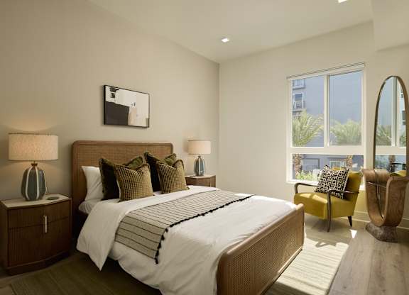A bedroom with a large bed, two lamps, and a chair.