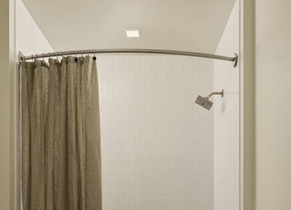 A bathroom with a shower curtain and a towel hanging on the door.