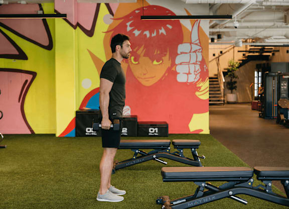A man is standing in a gym with a large mural in the background.