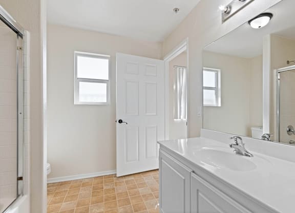 A bathroom with a white sink and a white door.