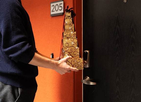 A person holding a bottle of champagne in front of a door with a number 205 on it.