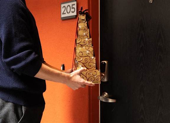 A person holding a bottle of champagne in front of a door with a number 205 on it.