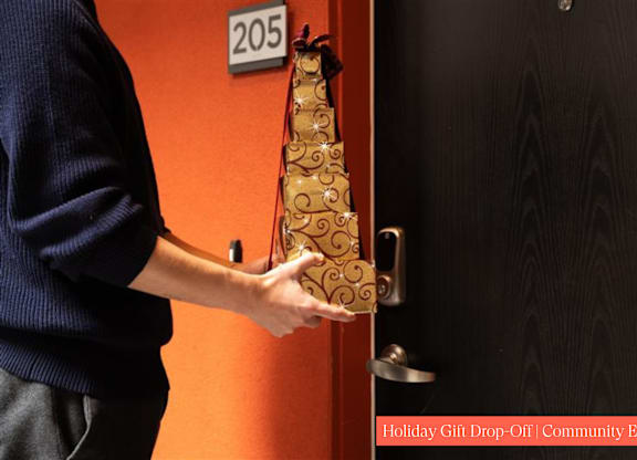 A person holding a gold-colored object with a number 205 on the wall behind them.