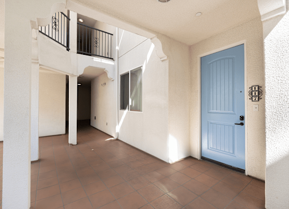 A blue door is on the right side of a white wall.