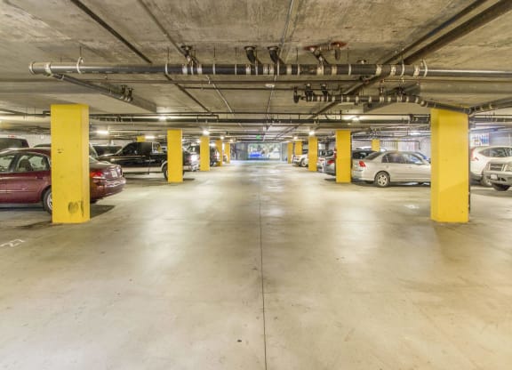 a parking garage with cars and yellow pillars at Dronfield Astoria Apartments, Sylmar