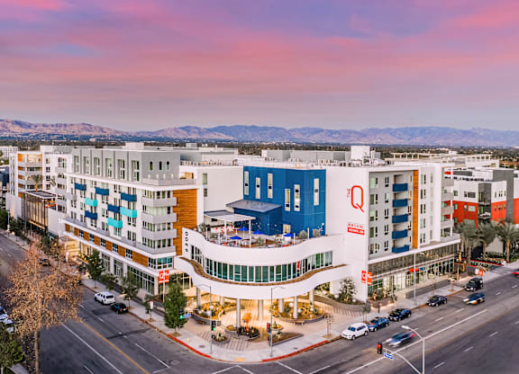 A large hotel with a blue and white building in the foreground and mountains in the background.