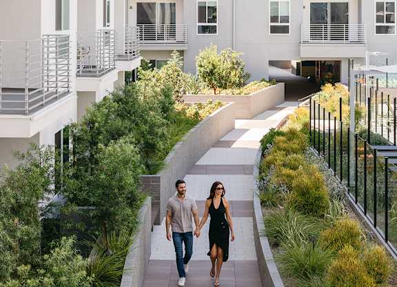 A man and a woman are walking down a path in front of a white building.