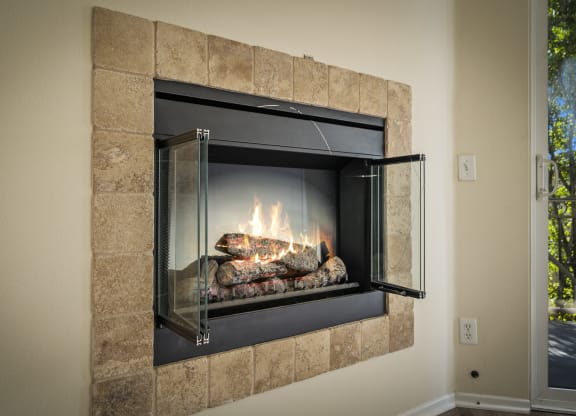 a fireplace with a glass door and rocks in the fireplace at The Village Apartments, Van Nuys California