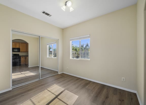 a bedroom with hardwood floors and beige walls at The Village Apartments, California, 91406