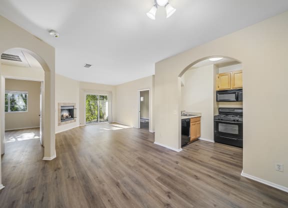 a living room and kitchen with hardwood floors and a fireplace at The Village Apartments, California