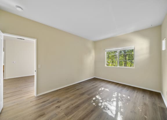 a bedroom with hardwood floors and beige walls at The Village Apartments, Van Nuys California