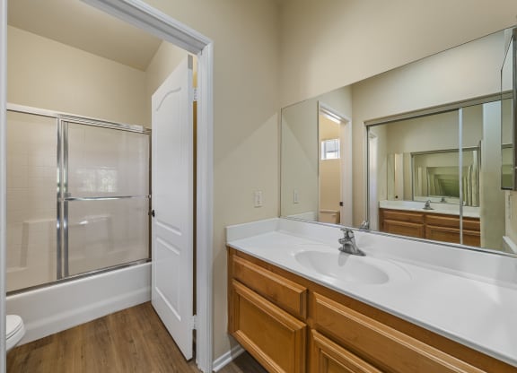 a bathroom with a large mirror and a large sink at The Village Apartments, Van Nuys, 91406