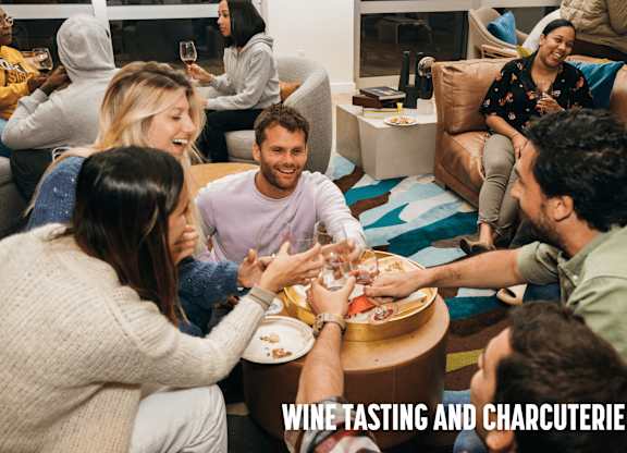 A group of people are gathered around a table for a wine tasting and charcuterie event.