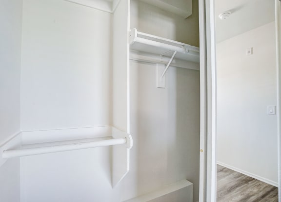 an empty closet with white walls and a white closet door