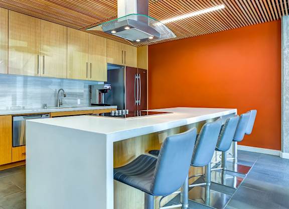 A modern kitchen with orange walls and a white island in the Aperture clubhouse