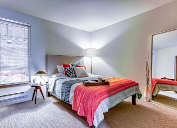 A bedroom with a bed, nightstand, and window
