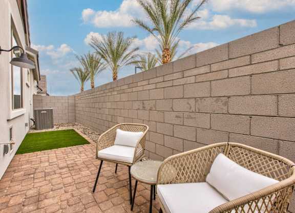 a patio with two chairs and a table next to a wall at Village of Chandler Apartments, Chandler, 85249