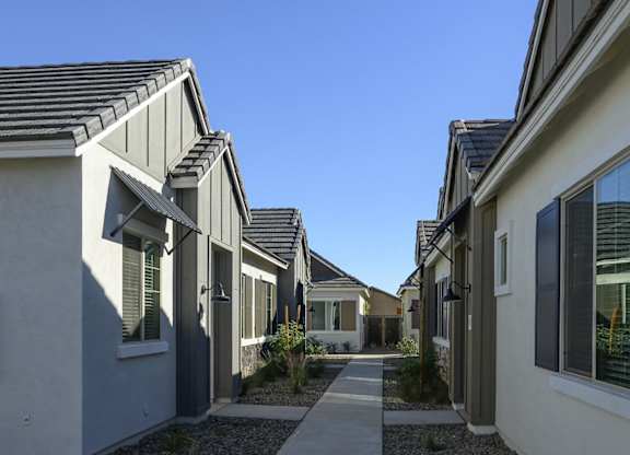 a row of houses with walkways between them and a blue sky at Village of Chandler Apartments, Chandler, Arizona