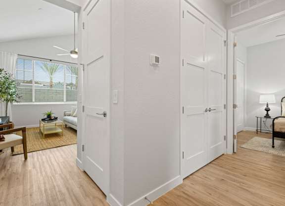 an open living room and dining room with white walls and wood floors at Village of Chandler Apartments, Arizona
