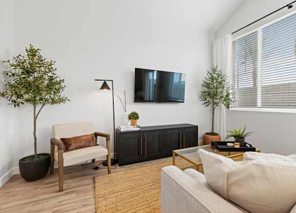 a living room with a couch and a tv on the wall at Village of Chandler Apartments, Chandler, AZ, 85249