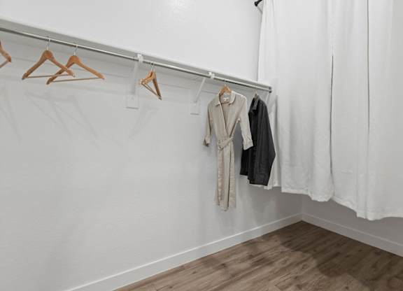 a white room with clothes hanging on a rack and a white curtain at Village of Chandler Apartments, Arizona