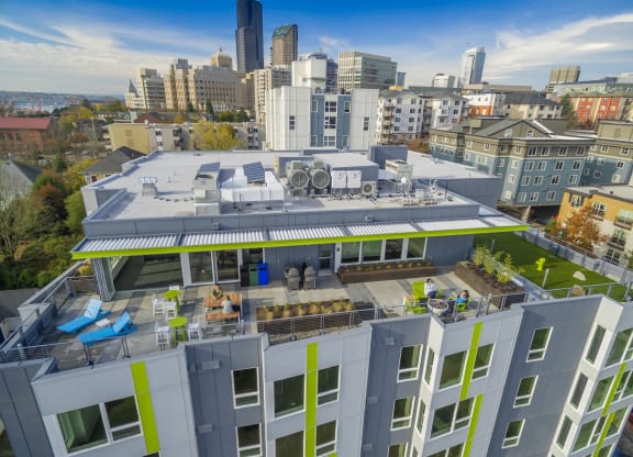 a rendering of a large building with a green roof and a cityscape in the background