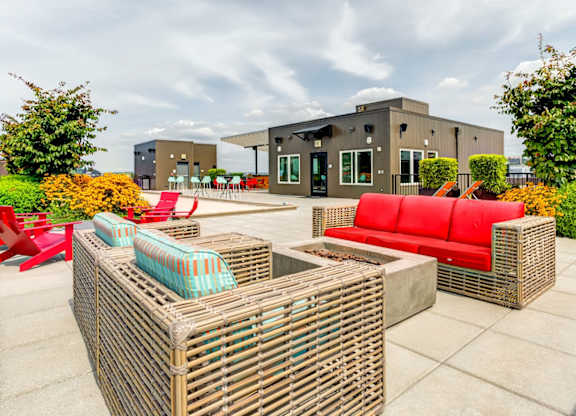 A roof top patio with a red couch and a wicker table