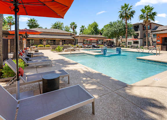 A pool area with a red umbrella and a small pool.