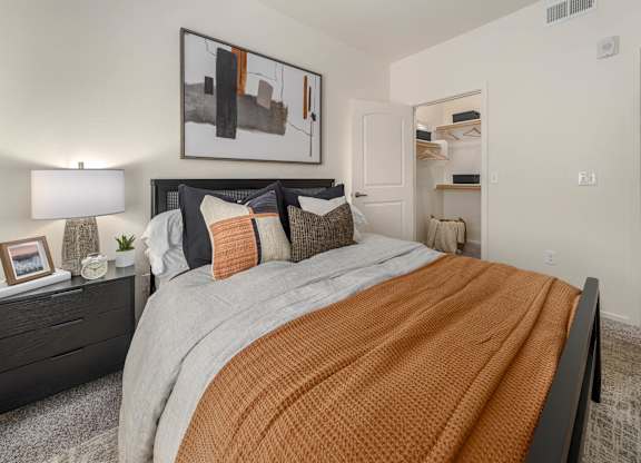 A bedroom with a large bed and a painting on the wall.