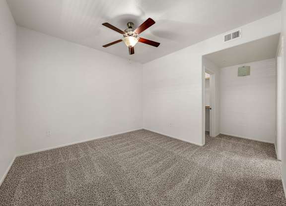 A room with a ceiling fan and carpeted floor.