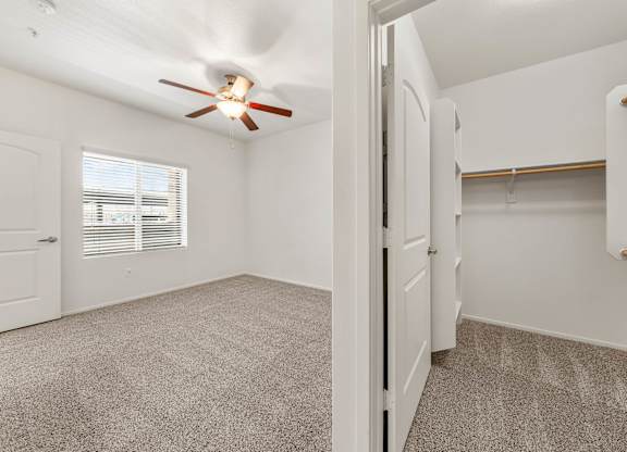 A room with a ceiling fan and carpeted floor.