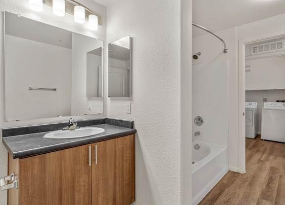 A bathroom with a sink, mirror, and a tub.