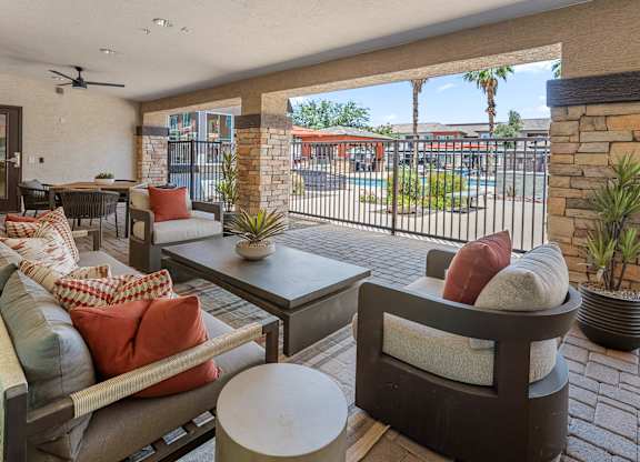 A patio with a couch, chairs, and a table with a potted plant.