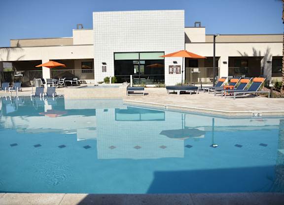 A swimming pool in front of a building with a white facade.