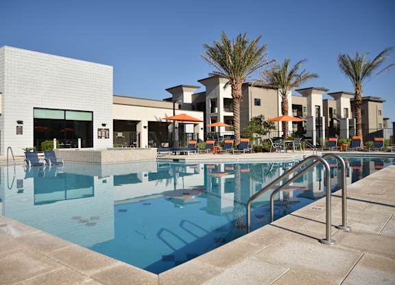 A swimming pool in front of a building with palm trees.