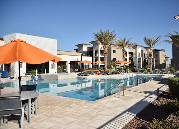 A pool area with a table and chairs and umbrellas.