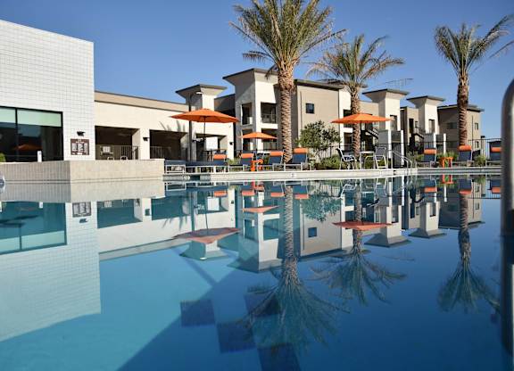 A pool in front of a building with palm trees.