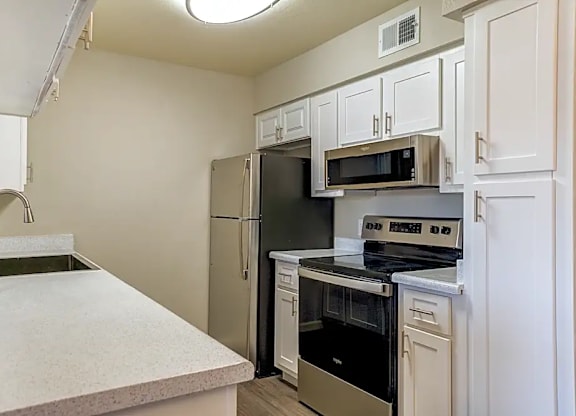 A kitchen with a stainless steel refrigerator, microwave, and oven.