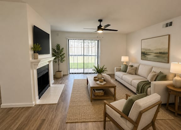 A living room with a fireplace, a couch, a chair, and a ceiling fan.