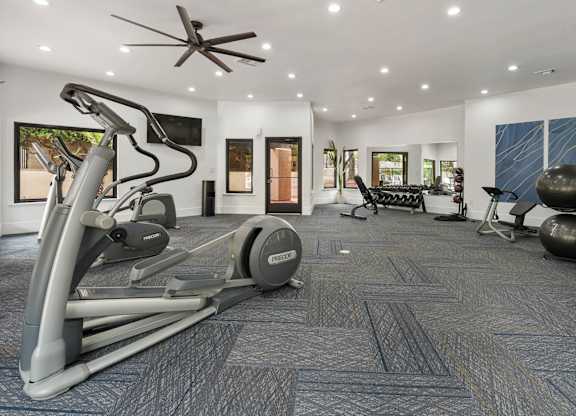 A home gym with a treadmill, weights, and exercise equipment.