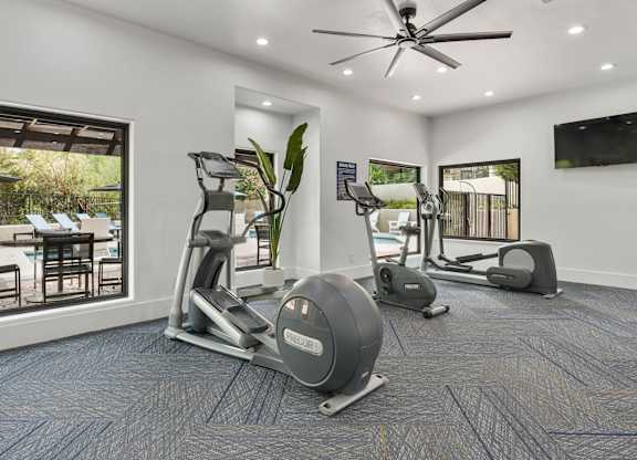 A spacious home gym with a treadmill, elliptical trainer, and stationary bike.