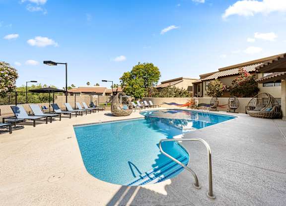 A pool with a slide and sun loungers.